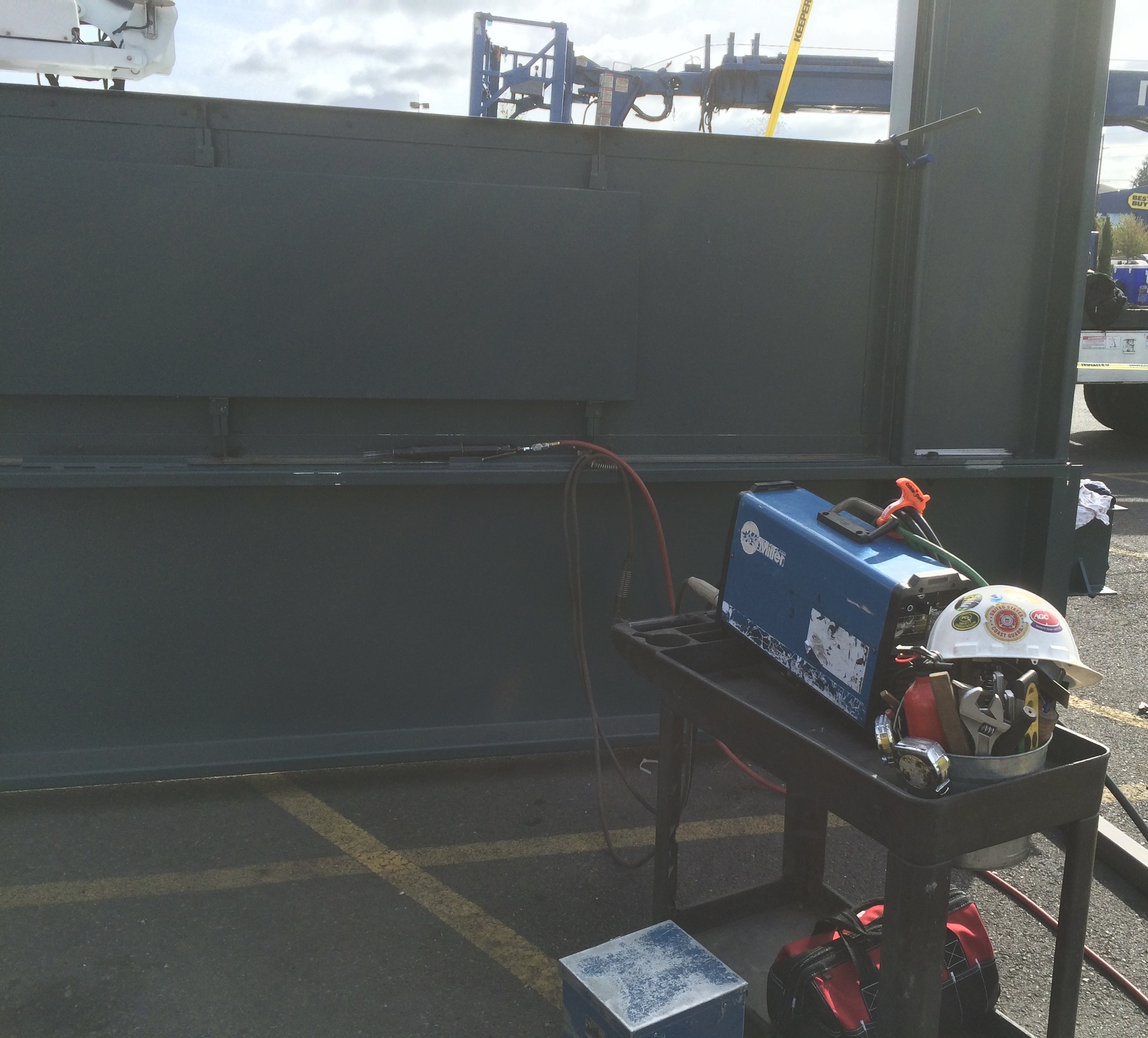 Welding equipment and safety helmet on cart near industrial wall