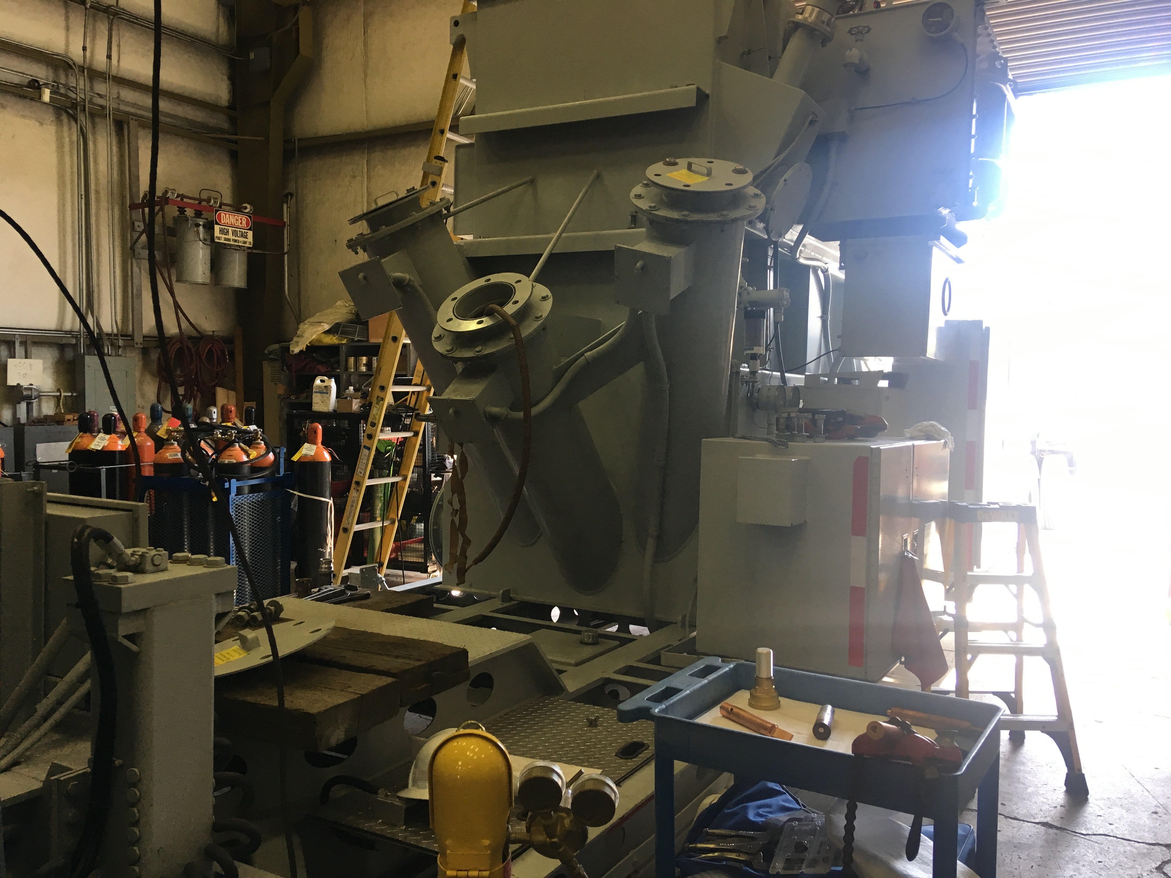 Industrial workshop with large machinery, ladders, and safety equipment