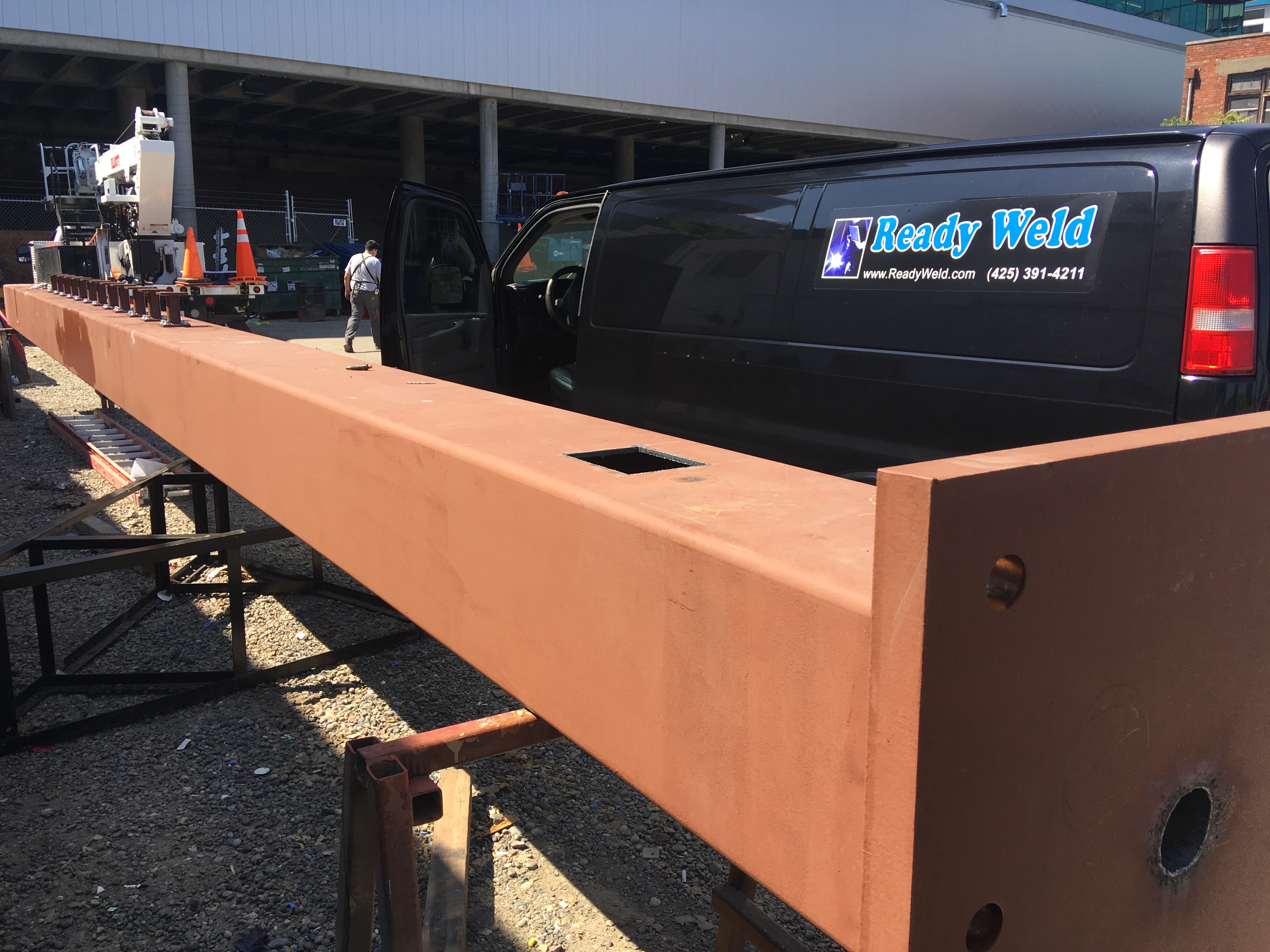 Ready Weld van parked next to long orange construction beam on work site