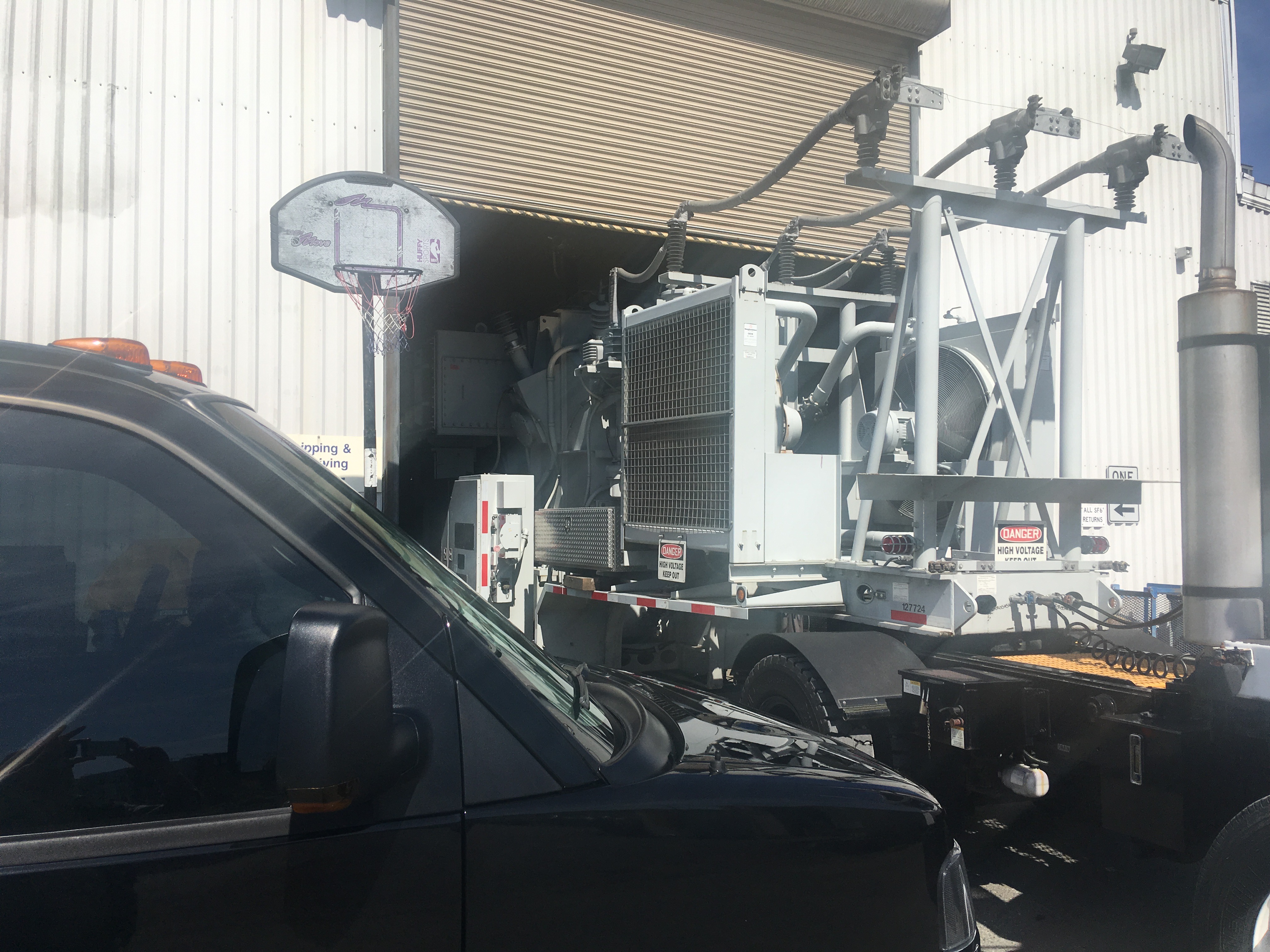 Industrial electrical equipment with basketball hoop in warehouse parking area